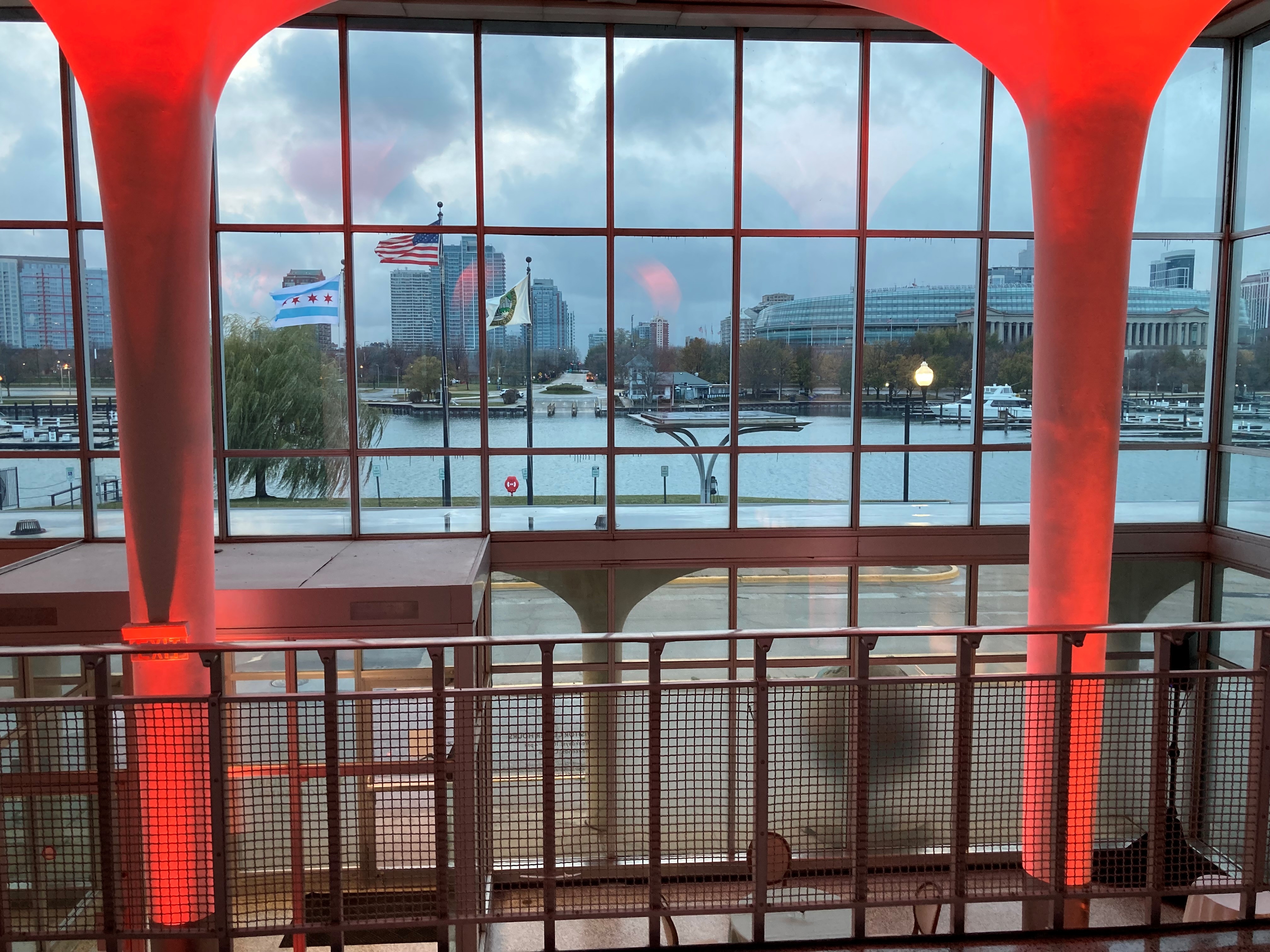 View of Chicago skyline, flags, and harbor through large windows with red lit columns.